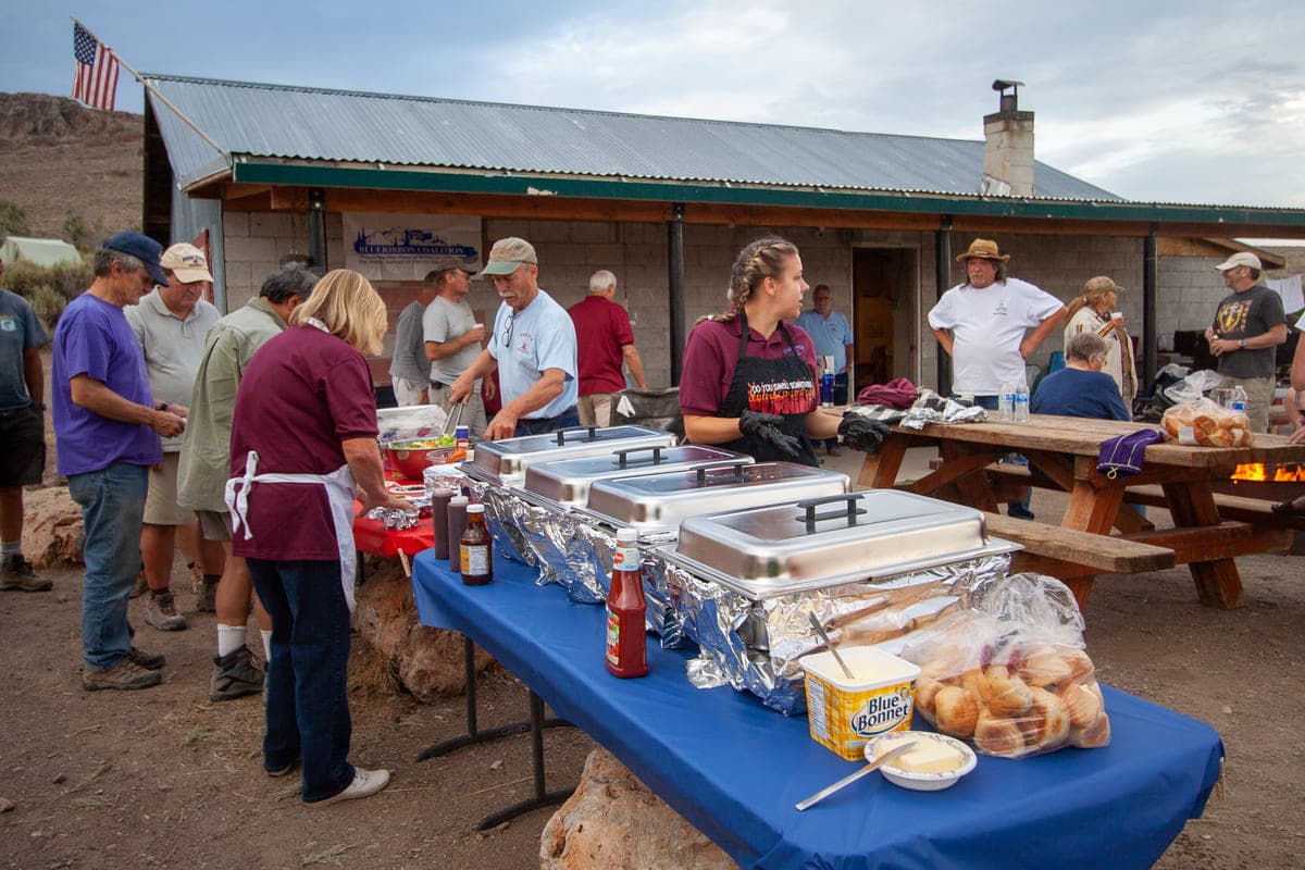 Club members serving and queuing for a meal at camp
