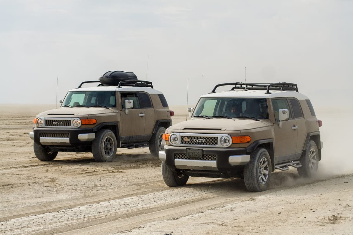 Two FJ Cruisers raising dust as they cross the playa