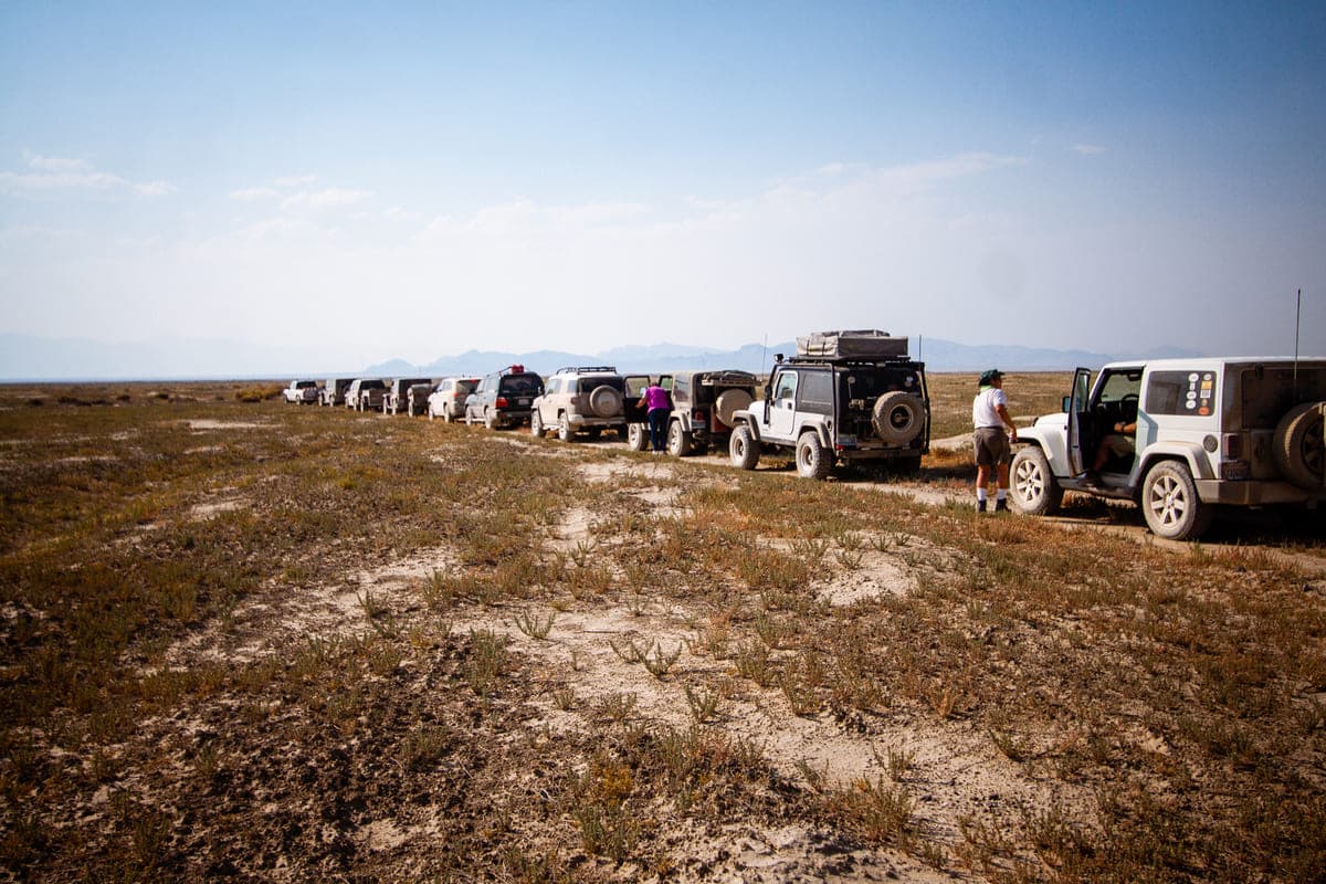 A line of four-wheel drives strung out along the trail across open sage flats